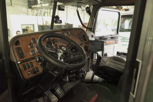 Inside of truck with steering wheel and gages.